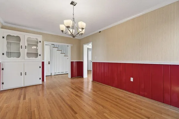 a view of an empty room with wooden floor and stairs