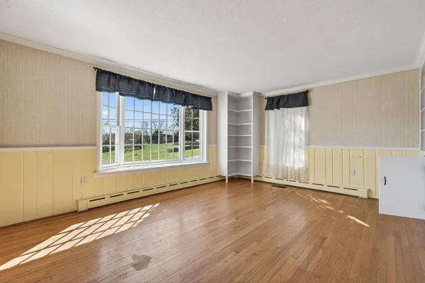 a view of an empty room with a window and wooden floor