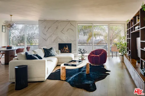 a living room with furniture a fireplace and a floor to ceiling window