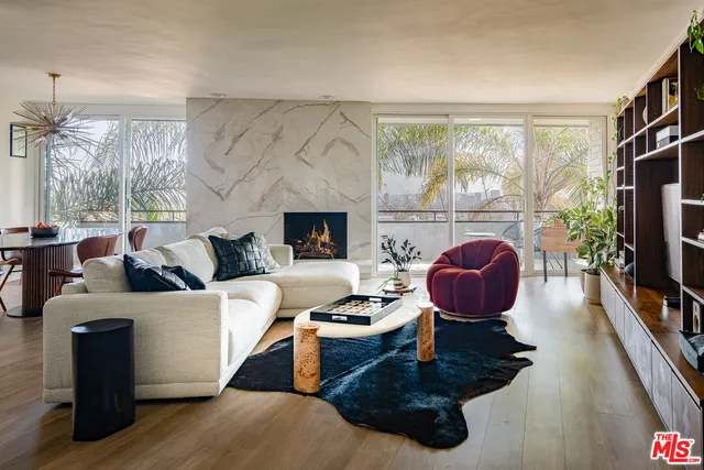 a living room with furniture a fireplace and a floor to ceiling window