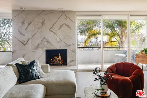 a living room with furniture a fireplace and a large window