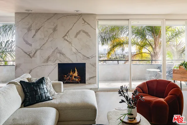 a living room with furniture a fireplace and a large window