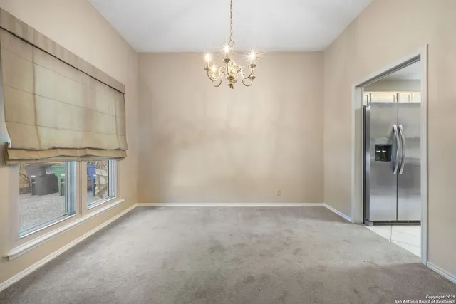 an empty room with chandelier fan and windows