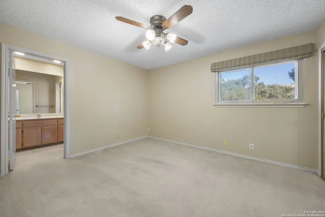 an empty room with a chandelier fan and a kitchen
