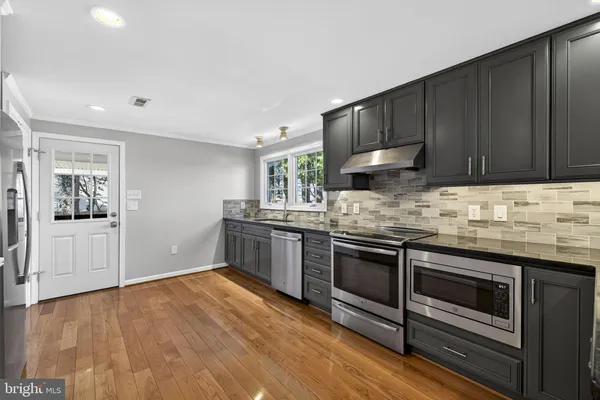 a kitchen with granite countertop wooden floors and stainless steel appliances