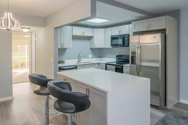 a kitchen with stainless steel appliances a stove a refrigerator and a dining table with wooden floor