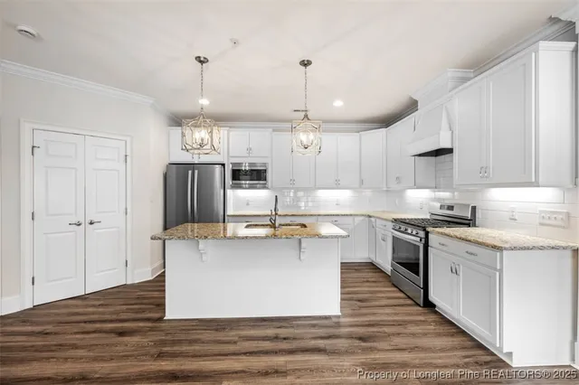 a kitchen with stainless steel appliances granite countertop a sink a stove and a refrigerator