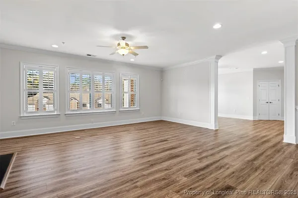 an empty room with wooden floor and windows