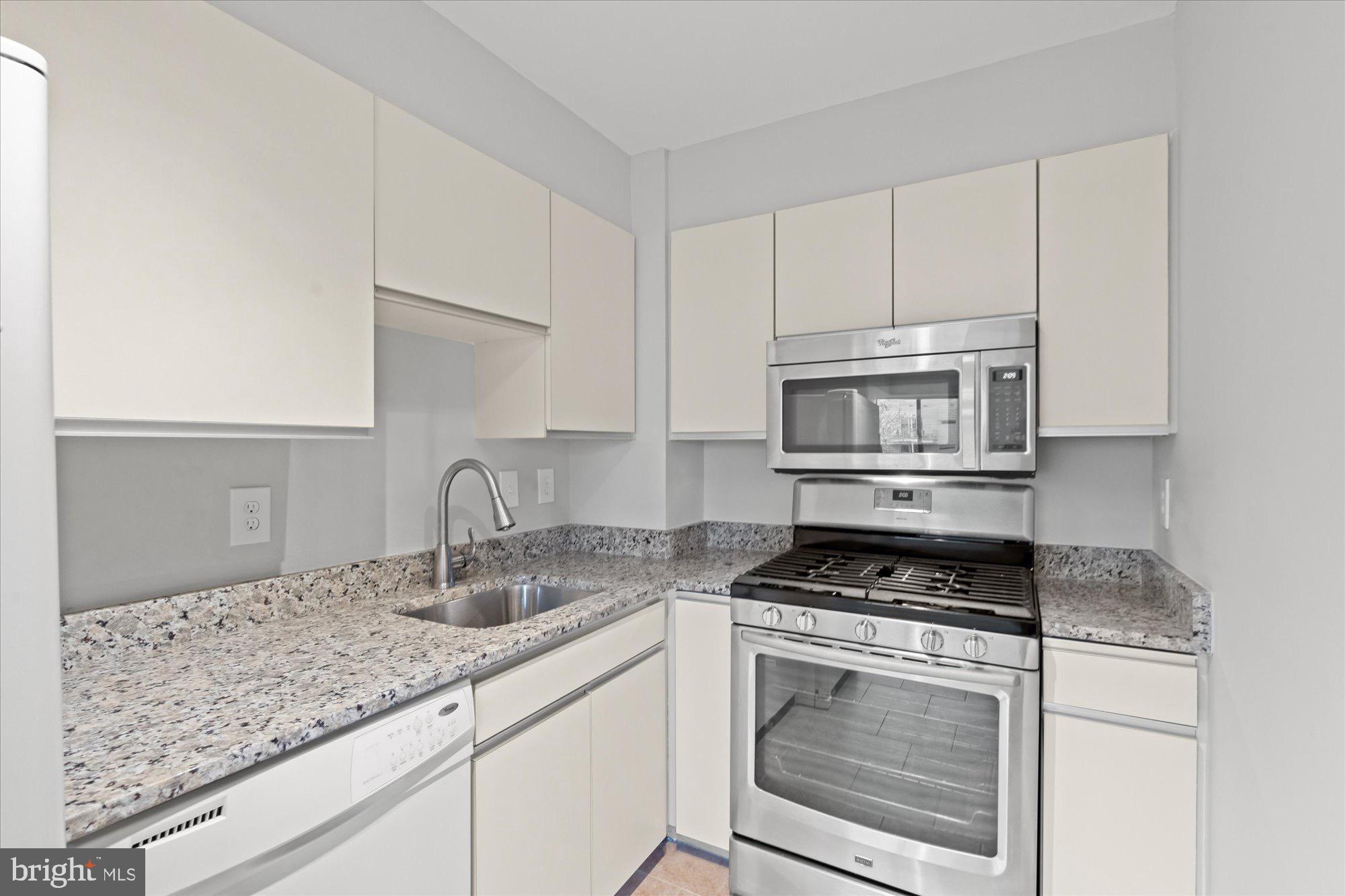 1245 13th Street Northwest, Unit 508 Washington, DC 20005 - Photo 7 of 15 a kitchen with granite countertop white cabinets sink and stainless steel appliances