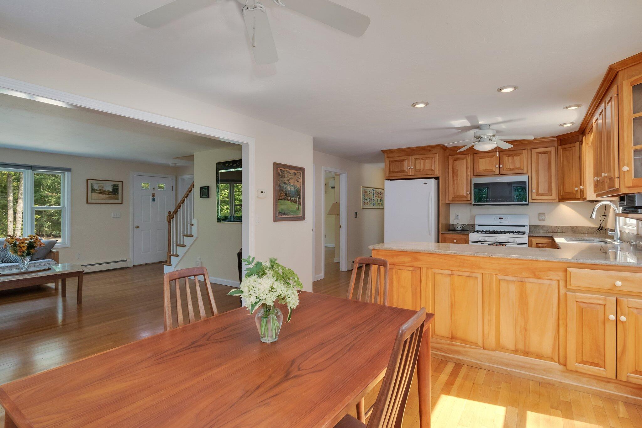 565 Sampsons Mill Road Cotuit, MA 02635 - Photo 17 of 87 a kitchen with stainless steel appliances granite countertop a stove top oven a sink dishwasher a dining table and chairs with wooden floor