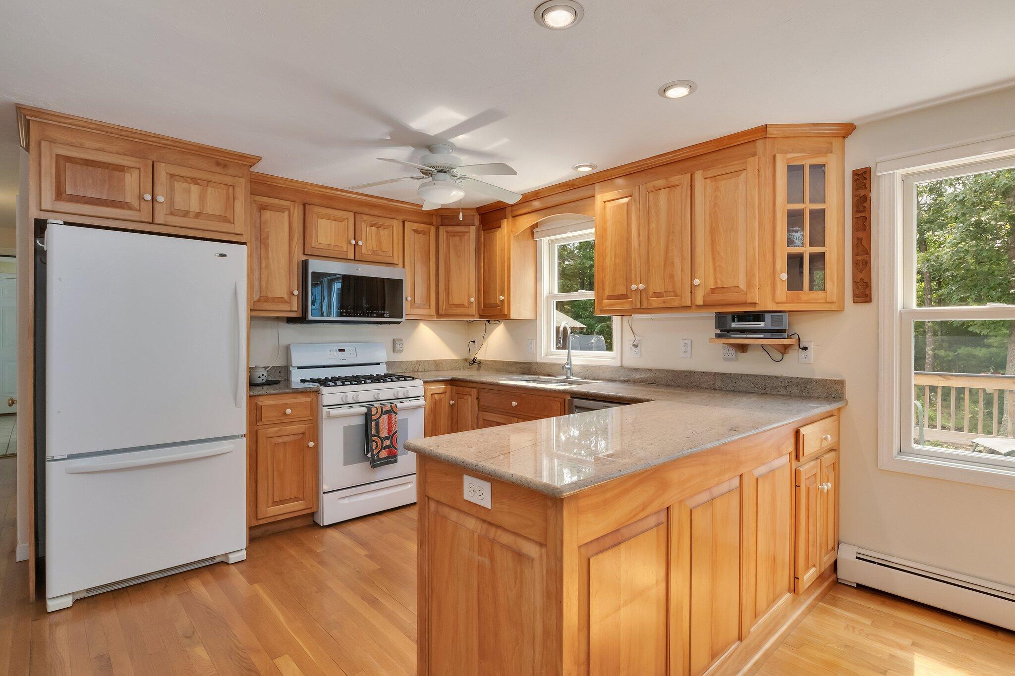 565 Sampsons Mill Road Cotuit, MA 02635 - Photo 18 of 87 a kitchen with stainless steel appliances granite countertop a refrigerator a stove a sink and a microwave