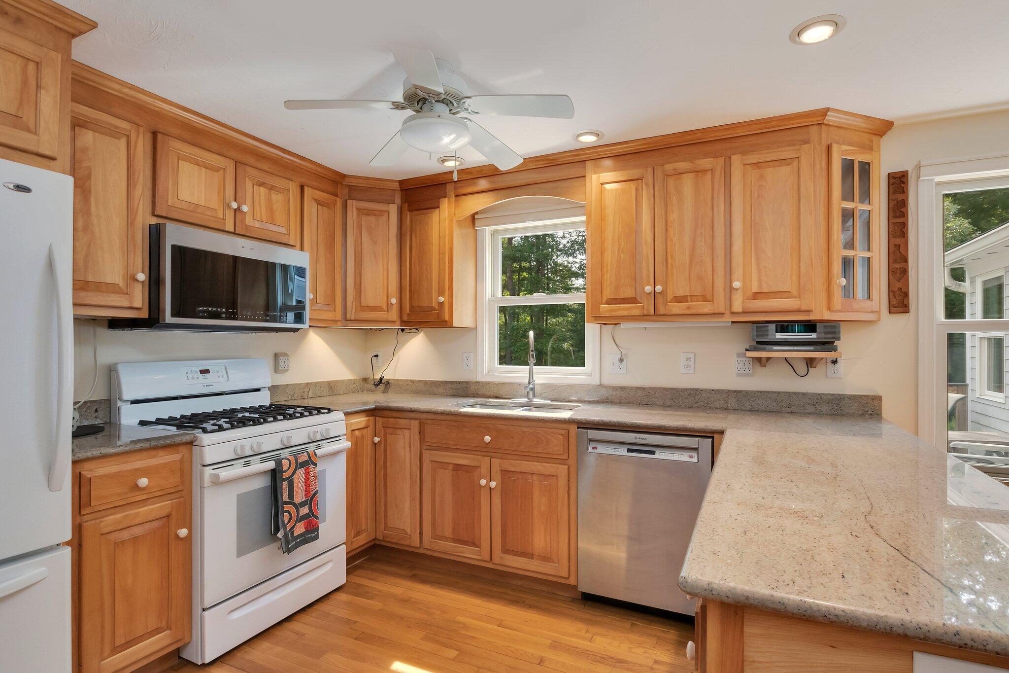 565 Sampsons Mill Road Cotuit, MA 02635 - Photo 19 of 87 a kitchen with stainless steel appliances granite countertop a stove top oven a sink dishwasher and white cabinets with wooden floor