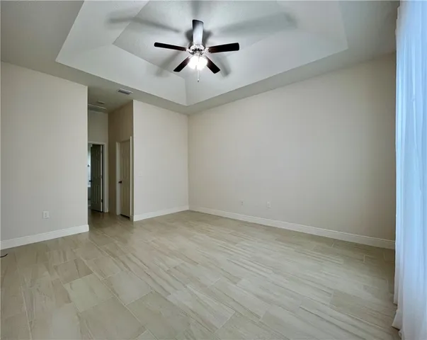 an empty room with ceiling fan and window