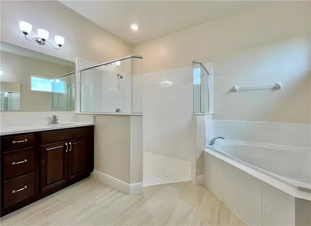 a bathroom with a tub sink shower and mirror