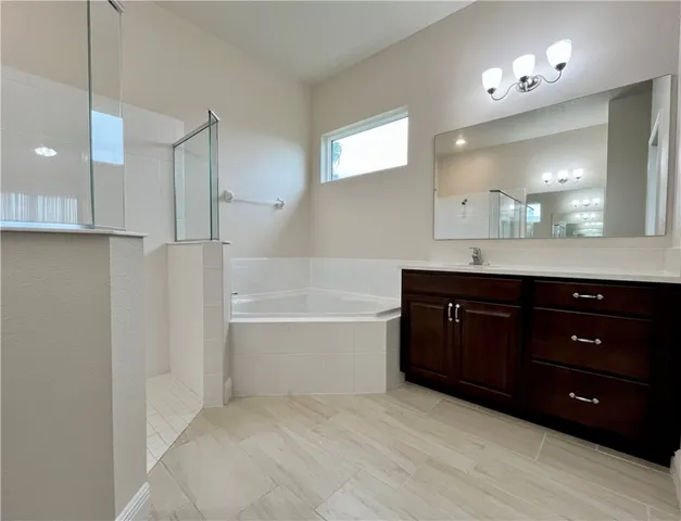 a spacious bathroom with a granite countertop double vanity sink a mirror and a bathtub