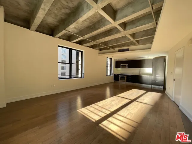 a view of empty room with wooden floor and windows