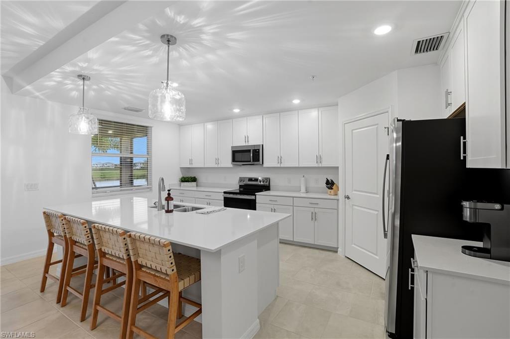 5667 Melbourne Court, Unit 7812 Ave Maria, FL 34142 - Photo 8 of 49 a kitchen with a refrigerator a stove a sink a dining table and chairs