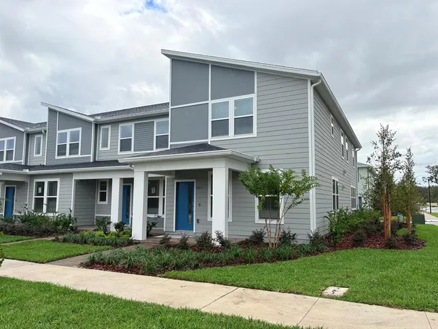 a front view of a house with a yard and potted plants