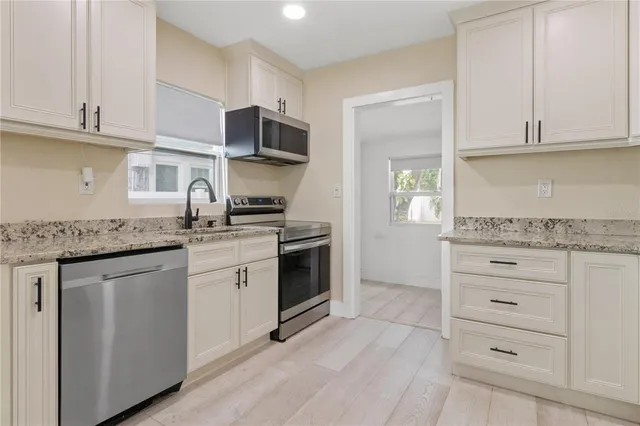 a kitchen with granite countertop white cabinets stainless steel appliances and a counter space