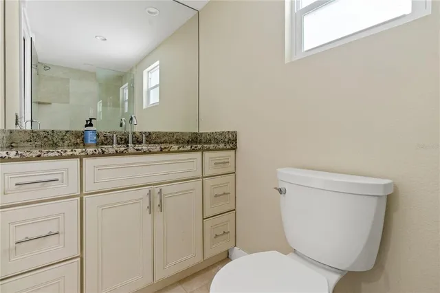 a bathroom with a granite countertop toilet sink and mirror
