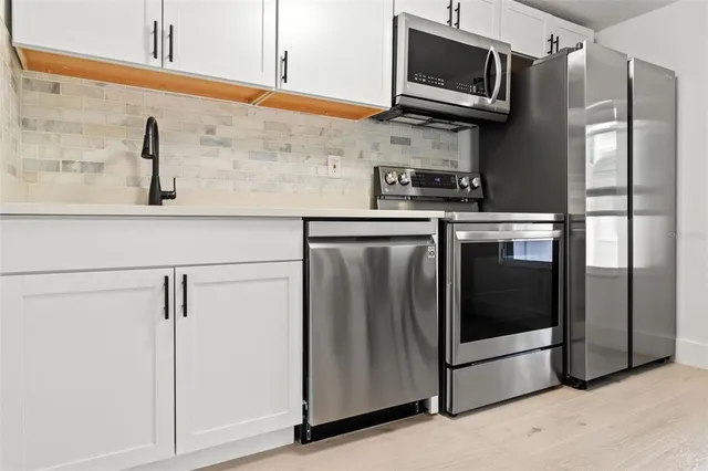 a kitchen with stainless steel appliances granite countertop a refrigerator and a stove top oven