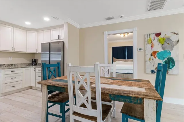 a kitchen with stainless steel appliances kitchen island granite countertop a table chairs and a refrigerator