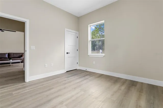 an empty room with wooden floor closet and windows