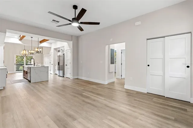 a view of an empty room with a ceiling fan wooden floor and a ceiling fan