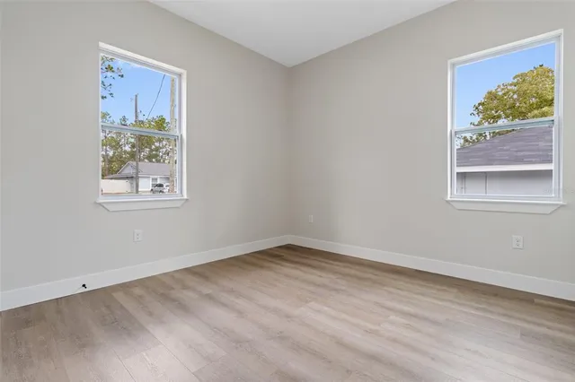 a view of an empty room with a window and wooden floor