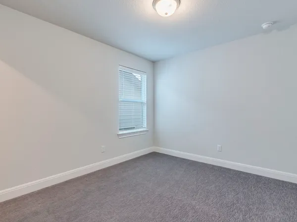 a bedroom with a bed a chair and potted plant on the dresser