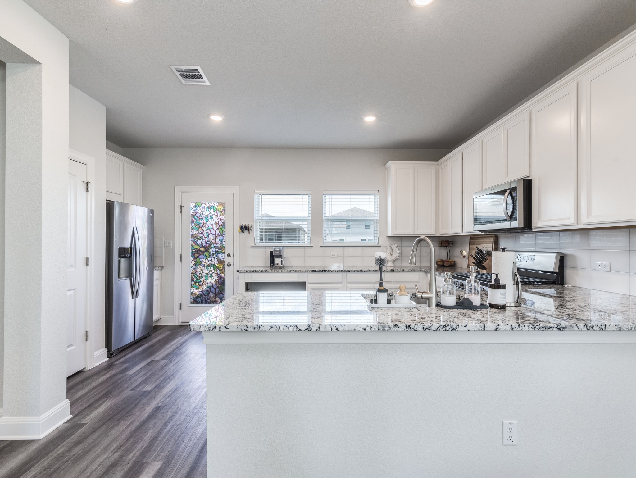 142 Mount Locke Road Dripping Springs, TX 78620 - Photo 7 of 31 a kitchen with stainless steel appliances granite countertop a refrigerator sink and white cabinets