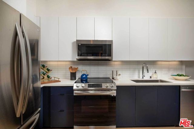 a kitchen with stainless steel appliances a sink a stove a refrigerator a sink a stove and cabinets