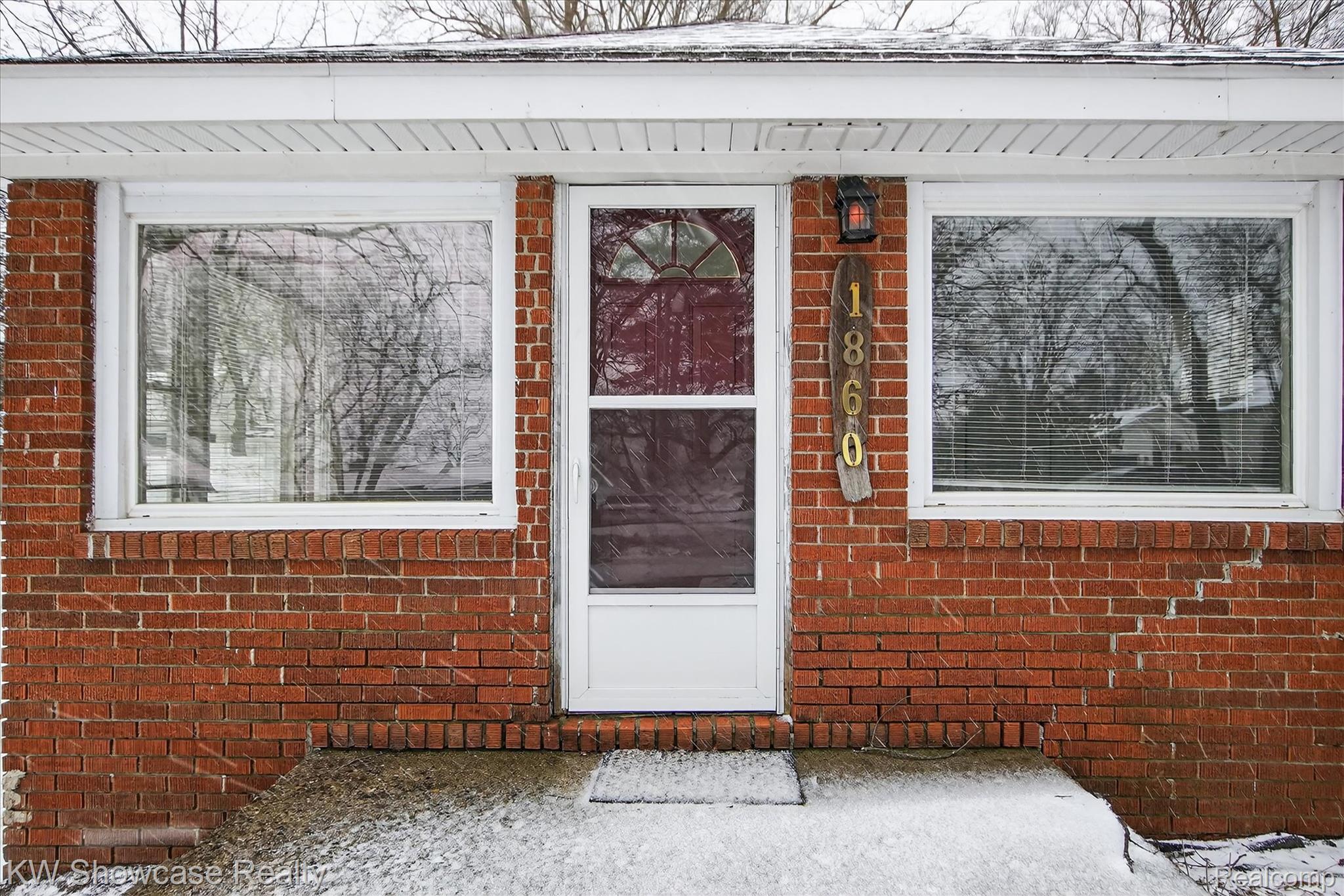 Snow covered property entrance with brick siding