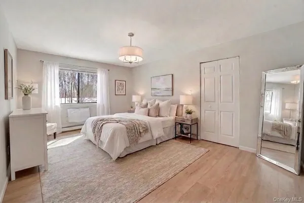 a spacious bedroom with a bed and dresser with wooden floor