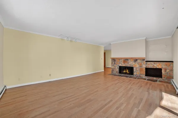 a view of empty room with wooden floor and fireplace