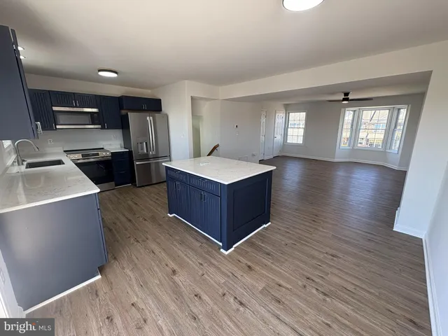a living room with stainless steel appliances kitchen island hardwood floor and a window