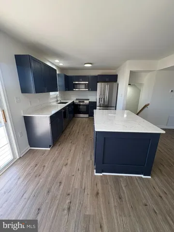 a living room with stainless steel appliances kitchen island wooden floors and living room view