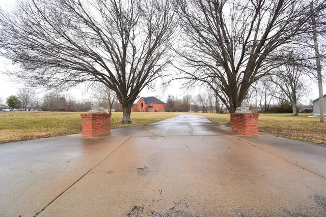a view of a big house with a yard and large tree