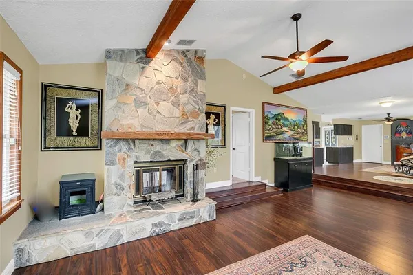a large dining hall with stainless steel appliances granite countertop a barbecue grill and couches with wooden floor