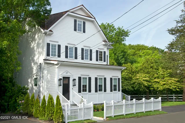 a view of a white house with large windows and plants