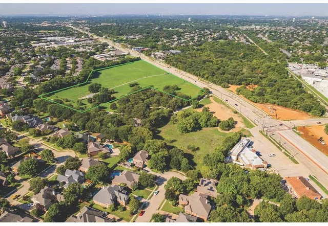 an aerial view of residential houses with outdoor space and trees