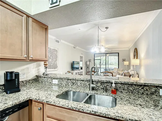 a kitchen with stainless steel appliances granite countertop a sink dishwasher a refrigerator and cabinets with wooden floor