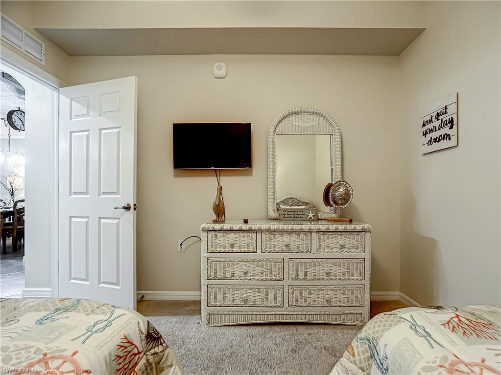 9554 Trevi Court, Unit 4715 Naples, FL 34113 - Photo 33 of 49 a bedroom with a bed and a flat screen tv
