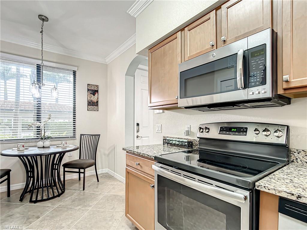 9554 Trevi Court, Unit 4715 Naples, FL 34113 - Photo 9 of 49 a kitchen with stainless steel appliances a stove a microwave sink and cabinets
