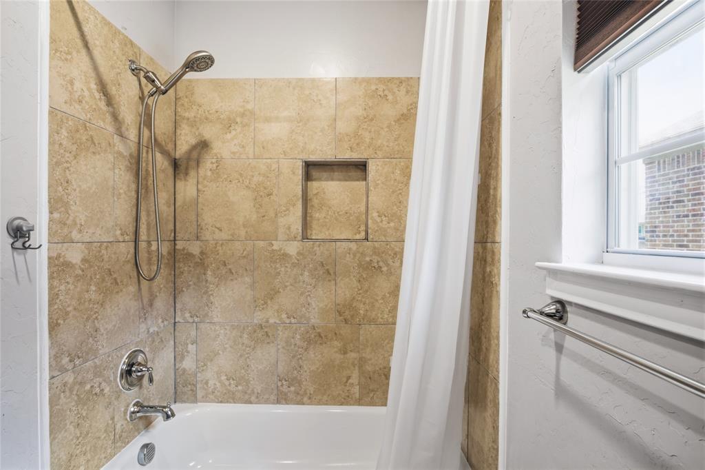 1502 Reed Street Greenville, TX 75401 - Photo 23 of 26 Bathtub and shower combination featuring a tiled surround, recessed shower niche, and polished chrome fixtures