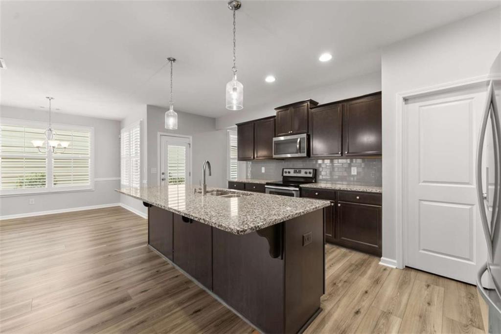 6021 Harbour Mist Drive Flowery Branch, GA 30542 - Photo 15 of 36 a kitchen with stainless steel appliances granite countertop a refrigerator a sink dishwasher a s kitchen island a stove and a wooden floors