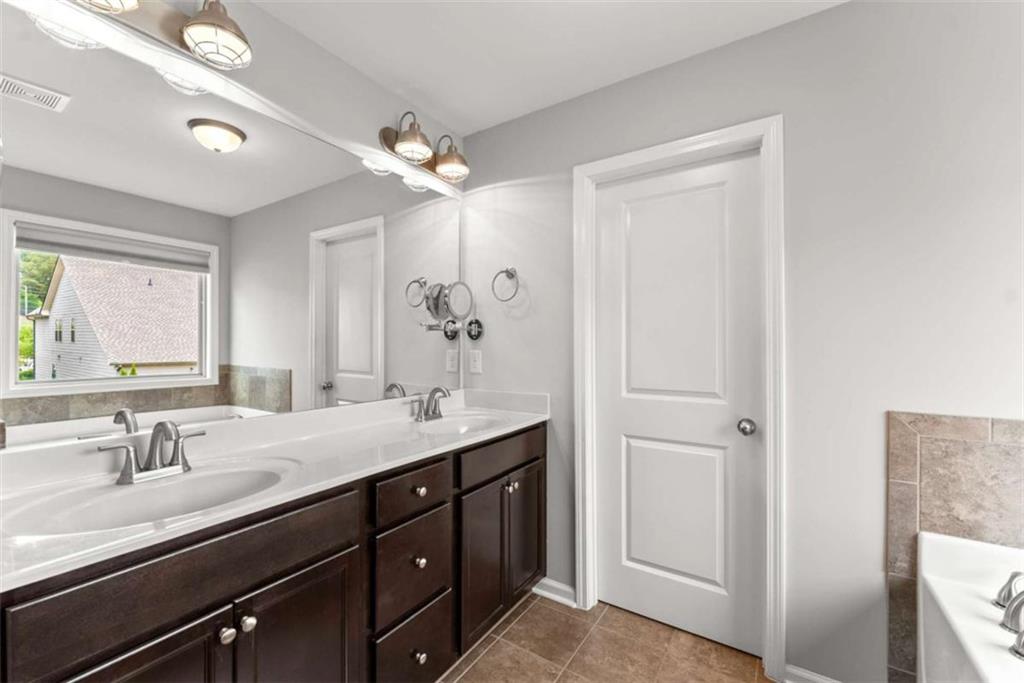 6021 Harbour Mist Drive Flowery Branch, GA 30542 - Photo 31 of 36 a bathroom with a granite countertop sink a large mirror and a