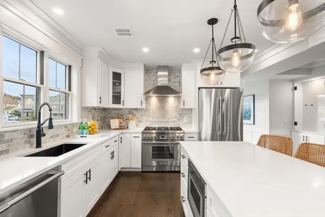 a kitchen with a sink stainless steel appliances a chandelier and a refrigerator