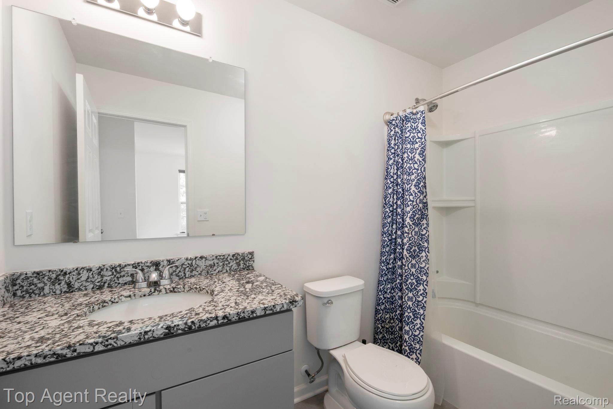 63770 Dequindre Road Washington, MI 48095 - Photo 32 of 61 Bathroom featuring a vanity with a granite-style countertop and undermount sink, a large mirror, and a full bathtub with shower surround
