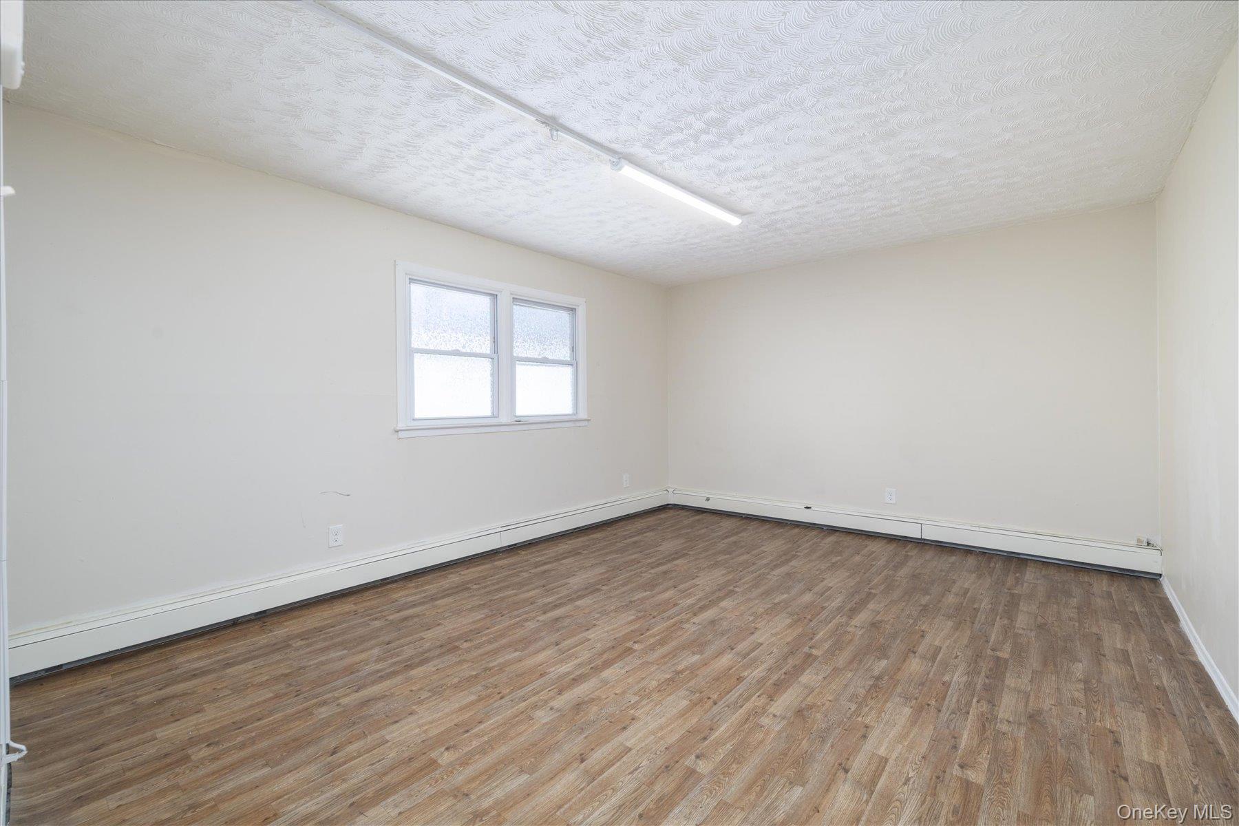 143 Wellington Road Elmont, NY 11003 - Photo 14 of 24 an empty room with wooden floor and windows